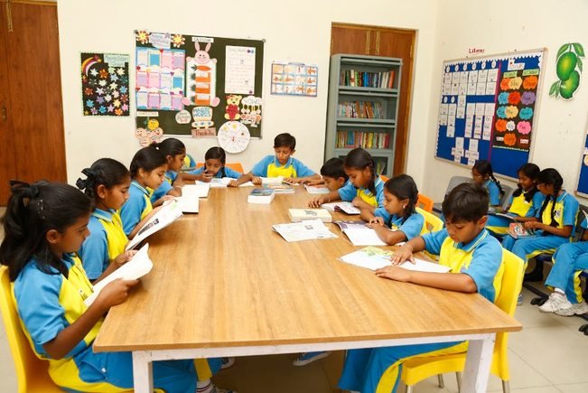 Primary students reading at the shared table in the school library