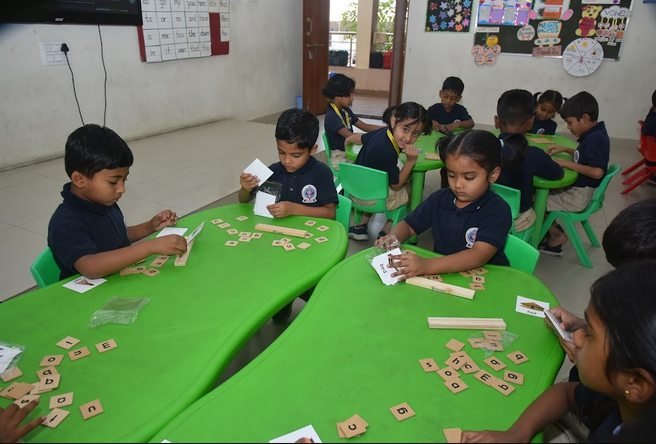 Young students working with letter tiles at their activity tables