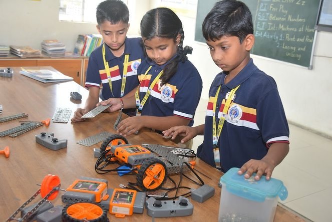 Three students assembling a wheeled robot during a robotics session