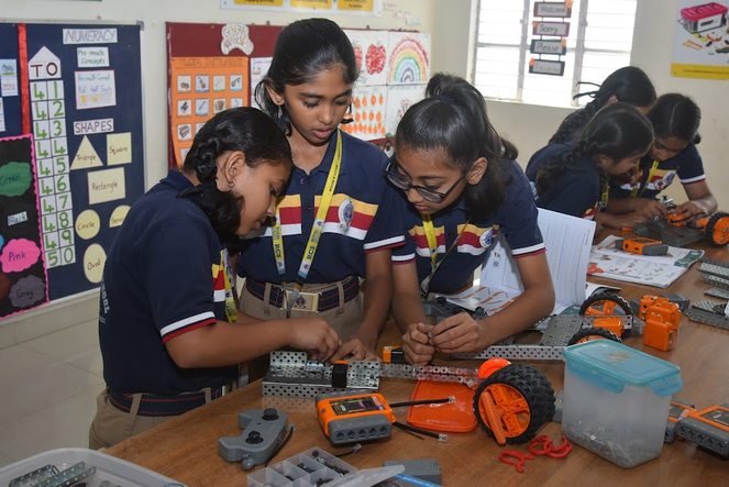 Students fitting components onto a robot chassis with tools