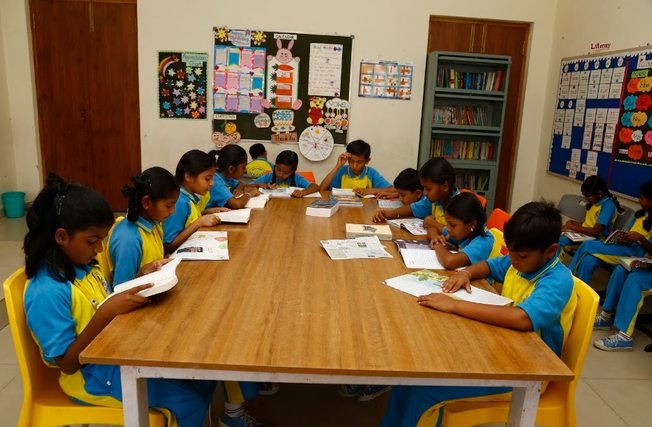 Primary students reading books at the shared library table